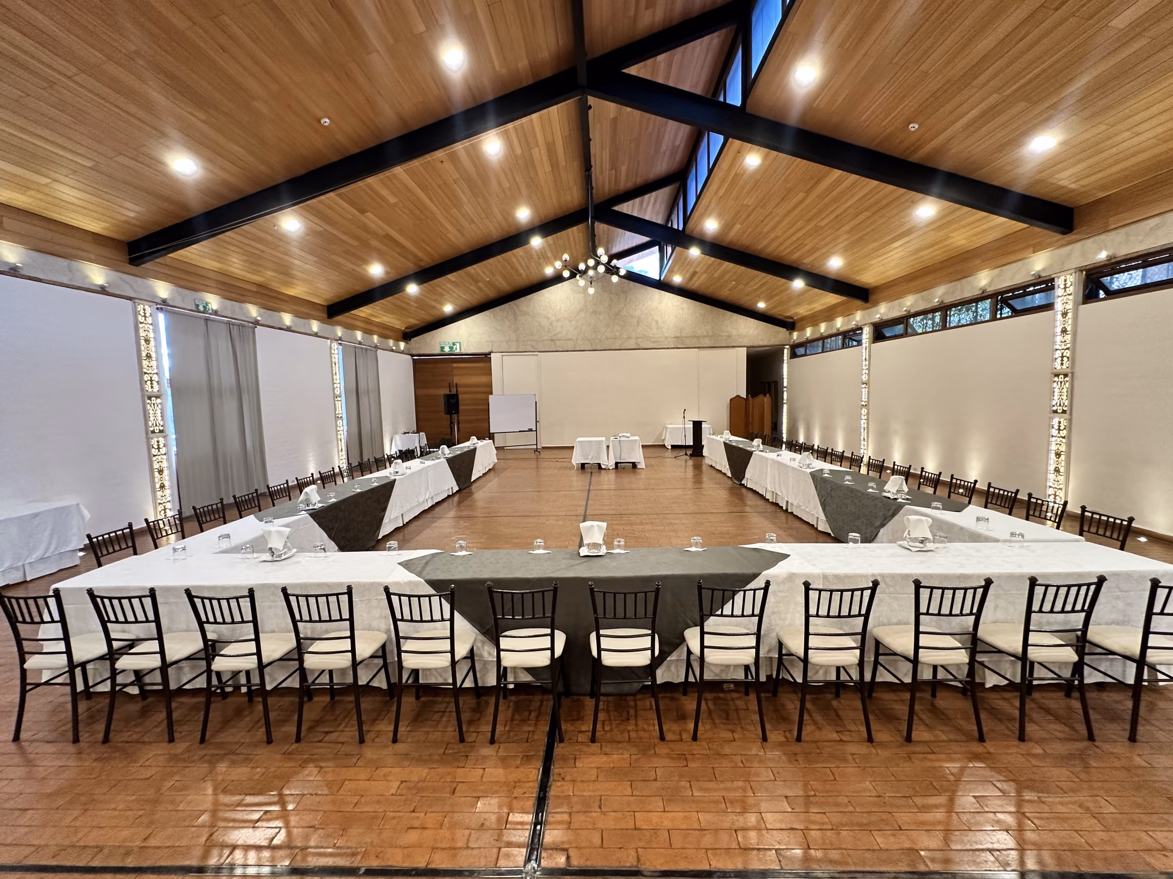 A U-shaped table set in the Los Sauces Hall for a working meeting.